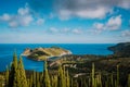 View to Assos village in sun light and beautiful blue sea. Green cypress trees in foreground. Kefalonia island, Greece