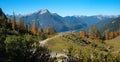 View to autumnal landscape with colorful larch trees and hill with resting bench, tirolean alps