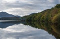A view to calm water of Loch Venachar, Trossarch, Scottish highlands and water reflection of forest and clouds Royalty Free Stock Photo