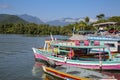 View to colorful tour boats in the water waiting for tourists at a pier, with green mountains in the background, Paraty, Brazil,