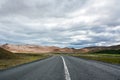 View to the empty curvy road, empty meadow and red mountains in the background in Myvatn region, Royalty Free Stock Photo