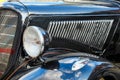 View to front grill, hood,fender and headlight  of a restored  classic vintage black car with blue cloudy sky reflection Royalty Free Stock Photo