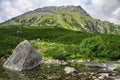 View to green mount and lake with massive rocks in front of it