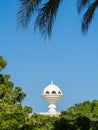 View to the Riyam Park monument dome through the palm leaves. Muscat, Oman. Royalty Free Stock Photo