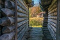 View to the small house in autumn forest through the narrow lane between two old log huts Royalty Free Stock Photo