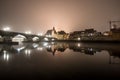 View to the stone bridge in Regensburg at night in the fog over the river Danube with the illuminated cathedral and historical old Royalty Free Stock Photo