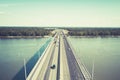 A view to the well-consrtucted city bridge across the river. City river gates. Cars on the bridge moving in and out of the city at