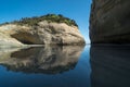 View to Wharariki Beach with huge cliff with greenery reflected in water, Collingwood, New Zealand