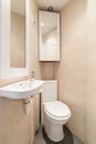 View of the toilet in the corner of compact tapered bathroom with beige mosaic tile, mirror, toilet and sink and wall Royalty Free Stock Photo