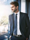 The view from the top. a handsome young businessman looking out of a window while standing in the office. Royalty Free Stock Photo