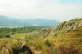 A view from the top of a high cliff to a beautiful valley in the mountains bathed in bright sunlight Royalty Free Stock Photo