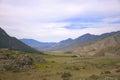 View from the top of the hill on the road running through the valley surrounded by high mountains Royalty Free Stock Photo