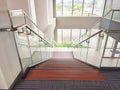 A view from the top of a modern wood staircase with glass side handrail hand guard in a buildinh