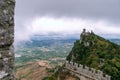 View from the top of the mountain to the medieval fortification. Dramatic mystical weather with fog. Castle in San Marino Second T