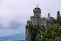 View from the top of the mountain to the medieval fortification. Dramatic mystical weather with fog. Castle in San Marino Second T