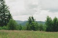 View from top mountain to wooded mountain landscape against background sky covered white-gray dense clouds. Royalty Free Stock Photo