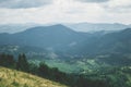 View from top mountain to wooded mountain landscape against background sky covered white-gray dense clouds. Royalty Free Stock Photo