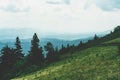 View from top mountain to wooded mountain landscape against background sky covered white-gray dense clouds. Royalty Free Stock Photo