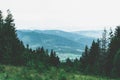 View from top mountain to wooded mountain landscape against background sky covered white-gray dense clouds. Royalty Free Stock Photo