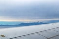 View of the top of Mt. Olympus in Greece poking out of a thick fog from an airplane with wing in foreground Royalty Free Stock Photo