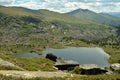 A view from the top of a rocky mountain to a large beautiful lake surrounded by mountain ranges on a summer morning Royalty Free Stock Photo