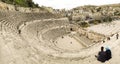 View from the top of the Roman Theatre, with tourists visiting and wandering around the roman ruins of Amman