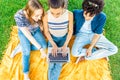 View from top of three gen z students sitting under a tree in city park using laptop to connecting with friends for online lessons Royalty Free Stock Photo