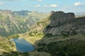 A view from the top to a picturesque lake lying in a lowland surrounded by high pointed rocks in the shade on a clear summer day Royalty Free Stock Photo