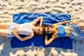 View from top of two cute girls in funny sunglasses lying on sand in ocean beach resort looking at camera. Two happy students Royalty Free Stock Photo
