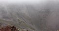 View from top of volcano to inactive crater in foggy weather