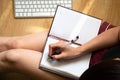 The woman writes in an open notebook with a black pen. Remote work at home Royalty Free Stock Photo