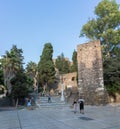 View at the tourist people visiting and strolling on Malaga Alcazaba building entrance, fortress and pedestrian path crossing with