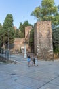 View at the tourist people visiting and strolling on Malaga Alcazaba building entrance, fortress and pedestrian path crossing with