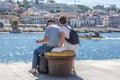 View of tourist senior couple seating on concrete bench on Ribeira docks