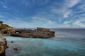 View of tourists exploring rocky cliff in scenic island against blue sky