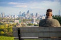 View towards London city skyline from Hampstead Heath through an tourist sitting on bench