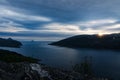 View towards the ocean from a view point above a fjord in Norway with sun and sun rays above the mountain ridge