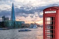 View from Tower Bridge against Thames river with tourist boat and red phone booth in London, England, UK Royalty Free Stock Photo