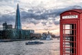 View from Tower Bridge against Thames river with tourist boat and red phone booth in London, England, UK Royalty Free Stock Photo