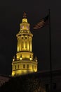 View of tower of Denver City Council at night. Lighted tower with clock on dark background. Waving American flag in foreground. Royalty Free Stock Photo