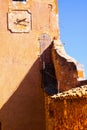 View on tower of fortress with clock and red ochre stone wall shadow with blue sky - Roussillon en Provence, France