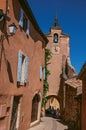 View of traditional colorful houses in ocher and clock tower, in Roussillon.