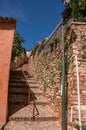 View of traditional colorful houses in ocher and stone staircase under a sunny blue sky, in Rous Royalty Free Stock Photo