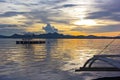 A view from traditional fishing boat with outriggers in lagoon of Coron Island at cloudy sunset.