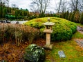 View of a traditional stone lantern ishi-doro surrounded by decorative boulders and bushes in a Japanese garden in Bonn