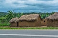 View of traditional village, house thatched on roof and terracotta walls, dramatic cloudy sky as background