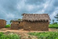 View of traditional village, house thatched on roof and terracotta walls, dramatic cloudy sky as background