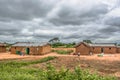 View of traditional village, people and thatched and zinc sheet on roof houses and terracotta brick walls, cloudy sky as Royalty Free Stock Photo