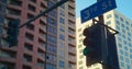 View traffic lights with blue sign number street on high buildings background.