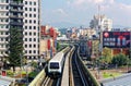 View of a train traveling on elevated rails of Taipei Metro System between an office tower & a commercial billboard